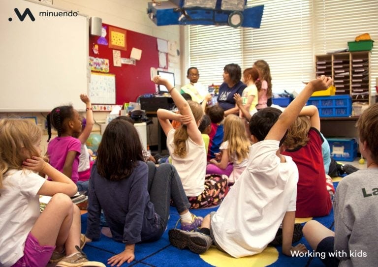 A group of children sitting on the floor in a classroom.