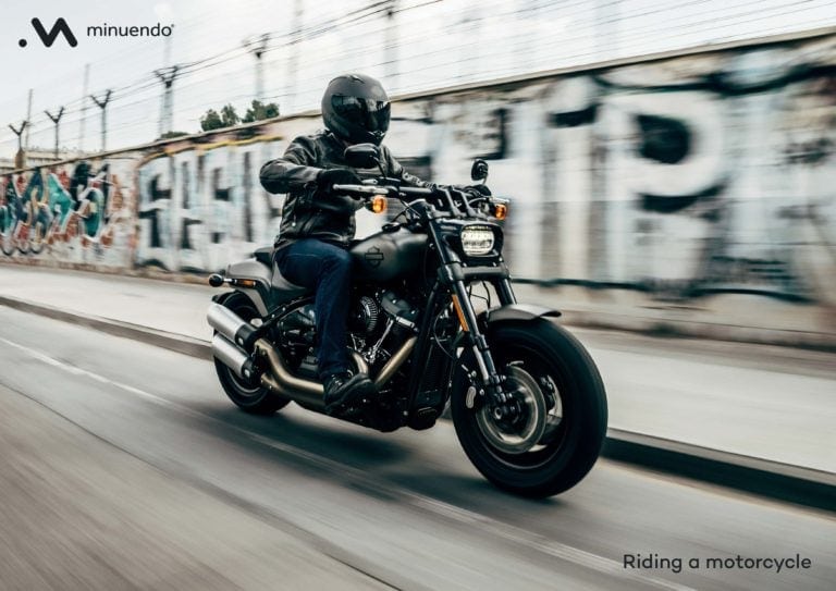 A man is riding a motorcycle down a street.