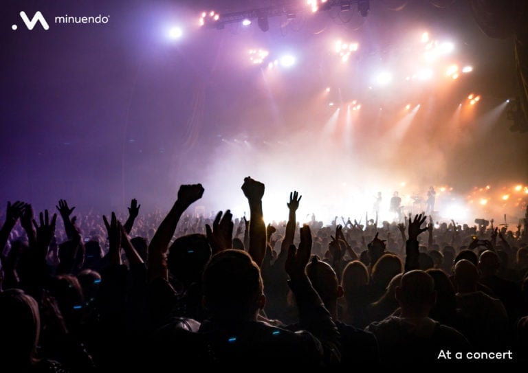 A loud concert with people raising their hands in the air.